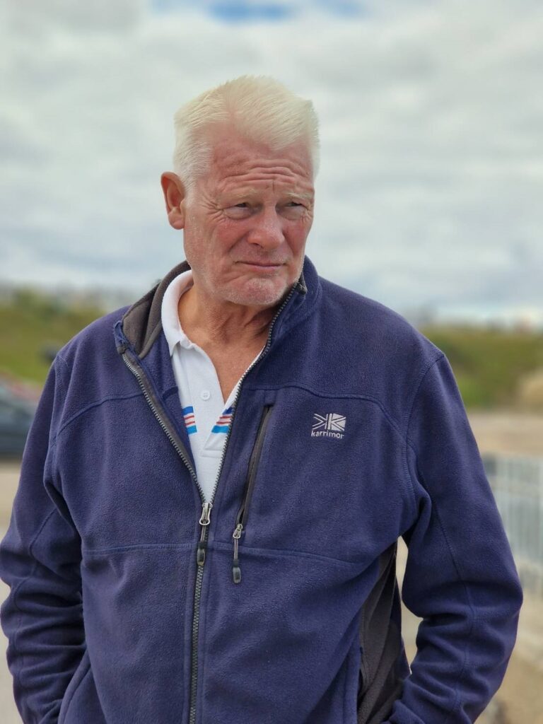Patient Robert Charlton is pictured outdoors with a blue fleece and t-shirt on.