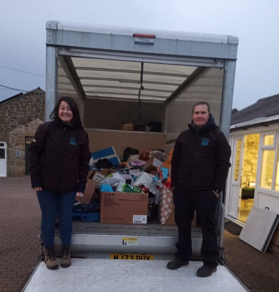 Picture of staff from Newcastle Dog and Cat Shelter stood on a removal van step with the boxes of donations in the van. 