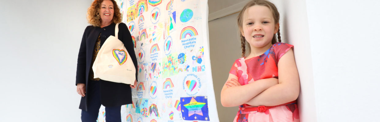 Libby and mum stood by drawings created by children of frontline NHS staff