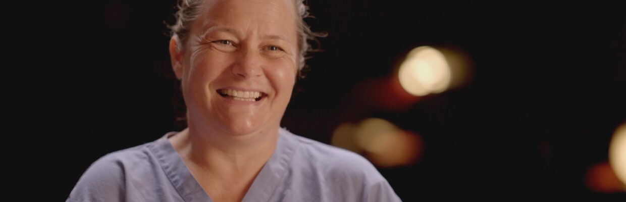 Lucy Clarke in blue scrubs smiling.