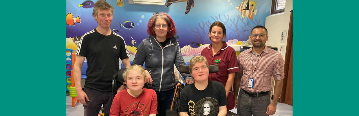 A picture of 6 people on a children's unit in hospital. There are toys on the floor and the wall behind is blue with fish on.